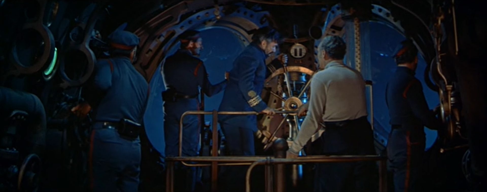 Technicolor scene with Captain Nemo on the bridge at the helm of the submerged Nautilus with some crew members present.