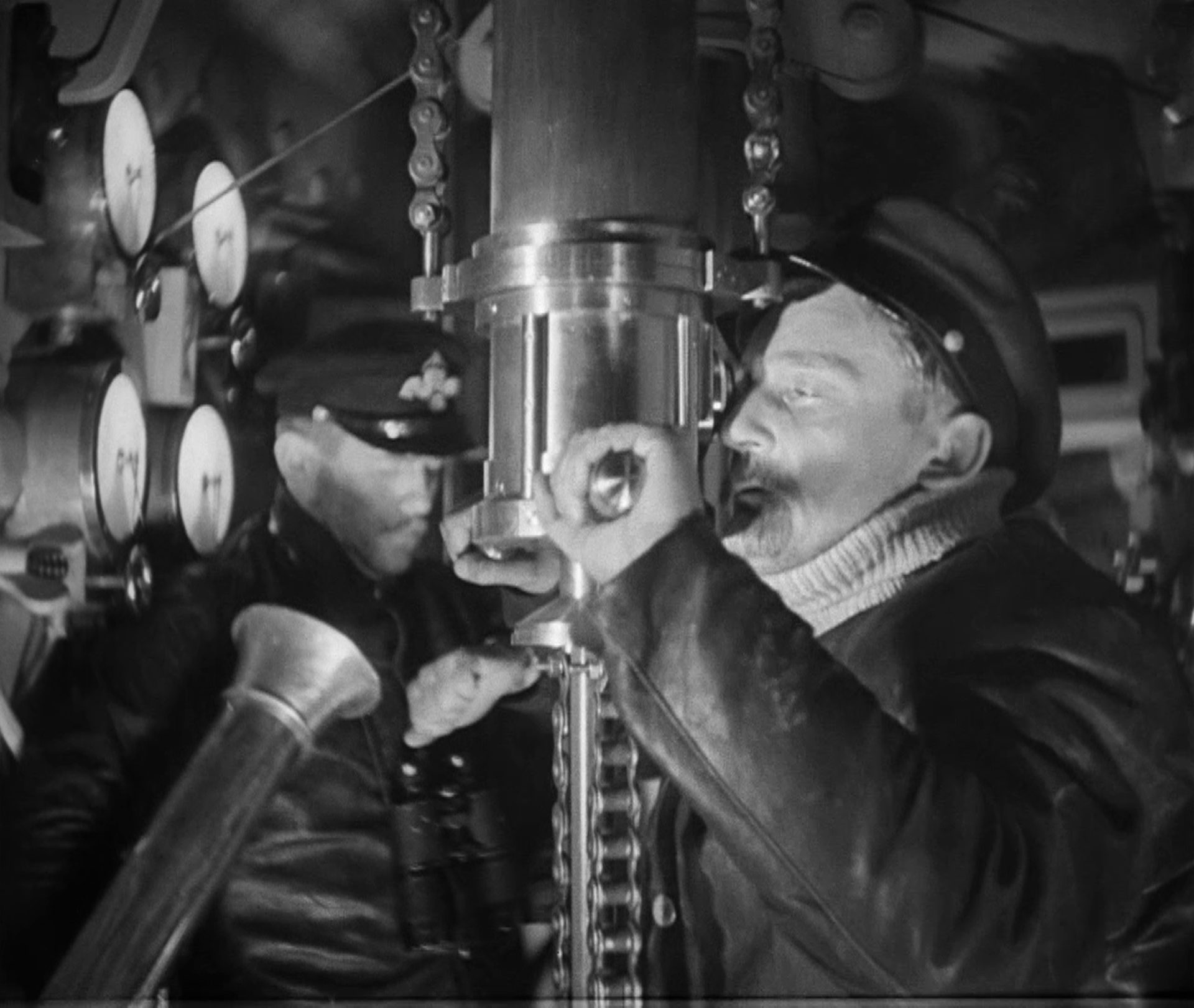Schwarz-Weiß-Szene mit Rudolf Forster als U-Boot-Kommandant beim Blick durch das Periskop.