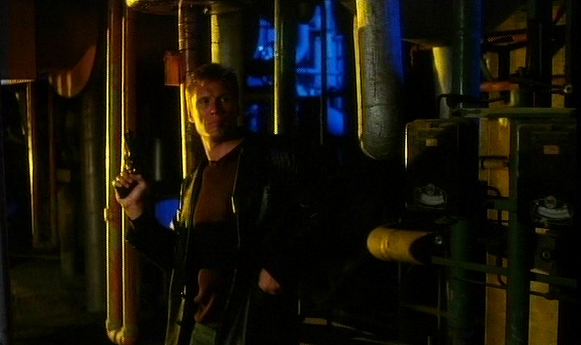 Dolph Lundgren mit Pistole in wachsamer Haltung in maschineller Umgebung im U-Boot.