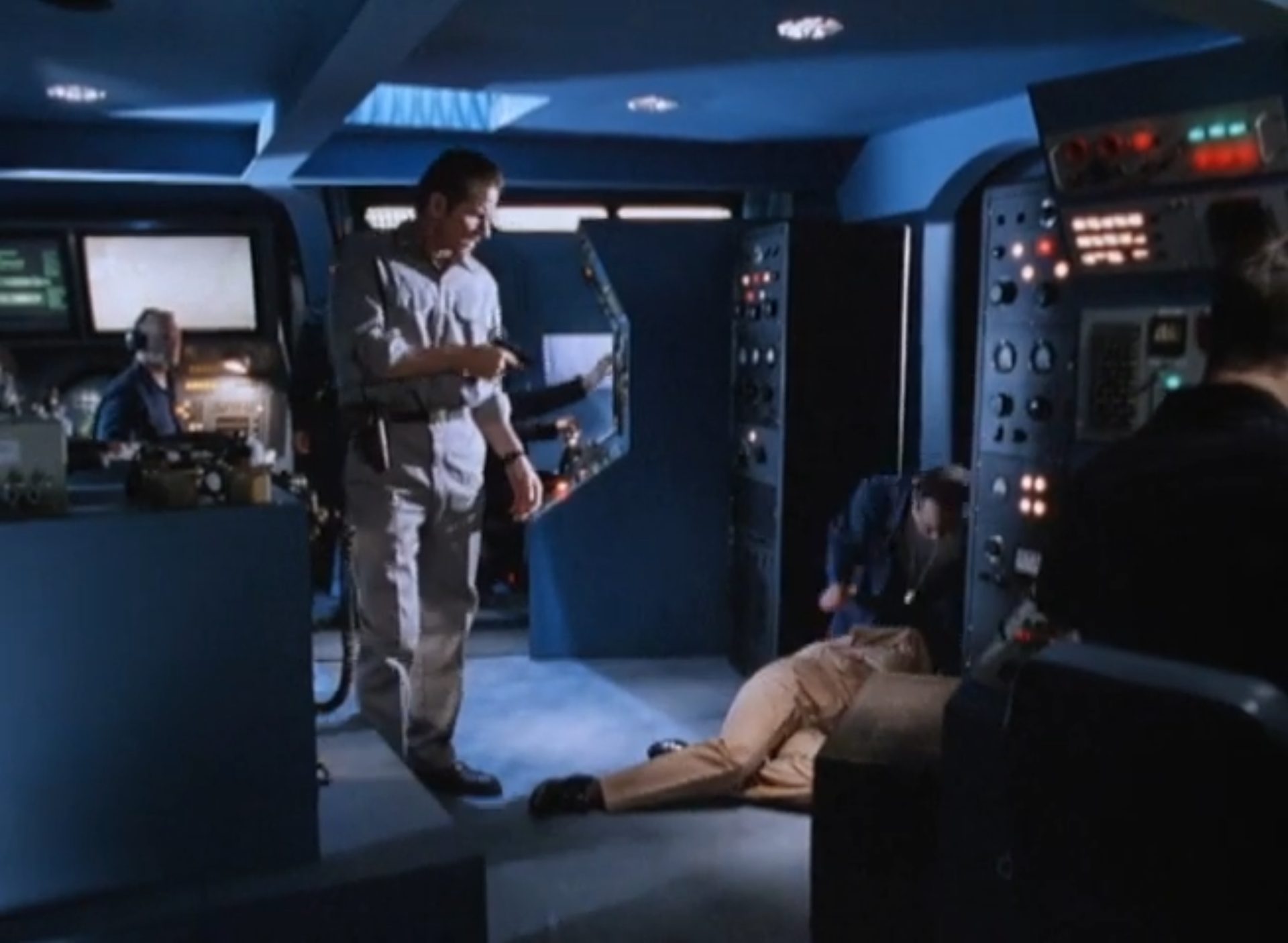 Hijacker in der Kommandozentrale des entführten U-Bootes, am Boden liegt jemand, hinter ihm steht einer der Kriminellen mit Pistole.