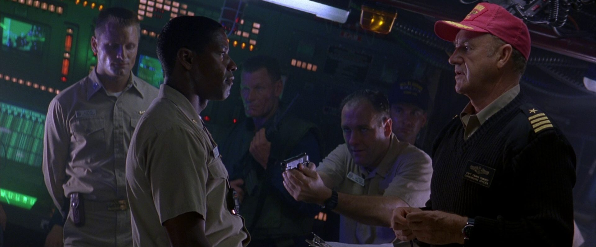 Confrontation between Denzel Washington as First Officer and Gene Hackman as Commander; a crew member points the gun at the first officer, in the background Viggo Mortensen as an officer with his eyes closed.