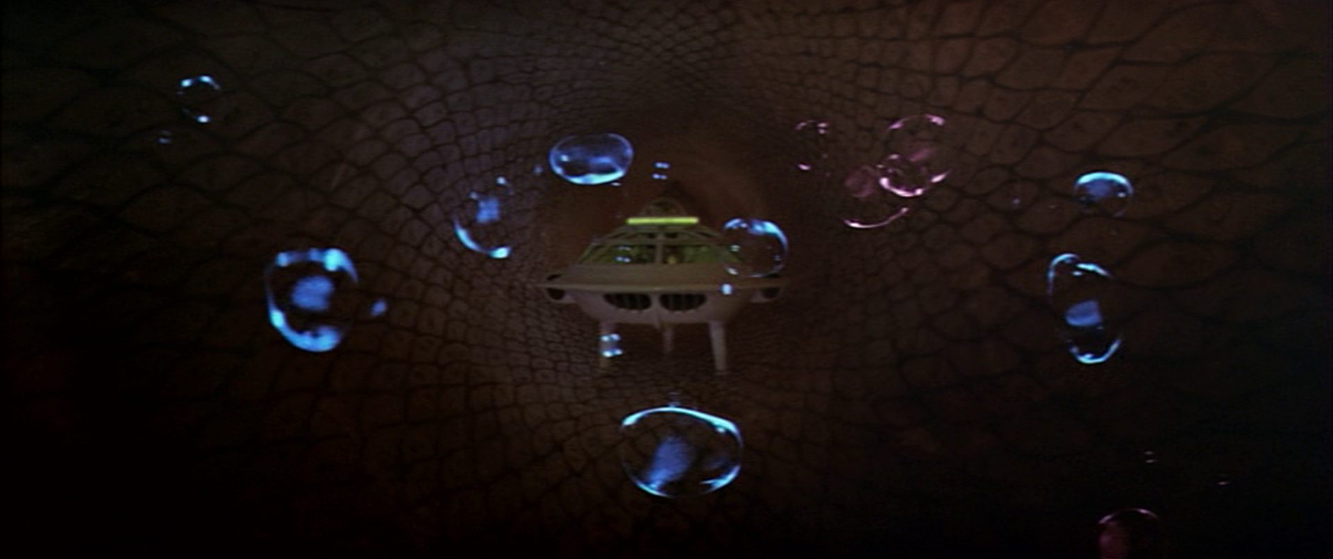 Frontal shot of the futuristic submarine in the human body, surrounded by transparent bubbles.