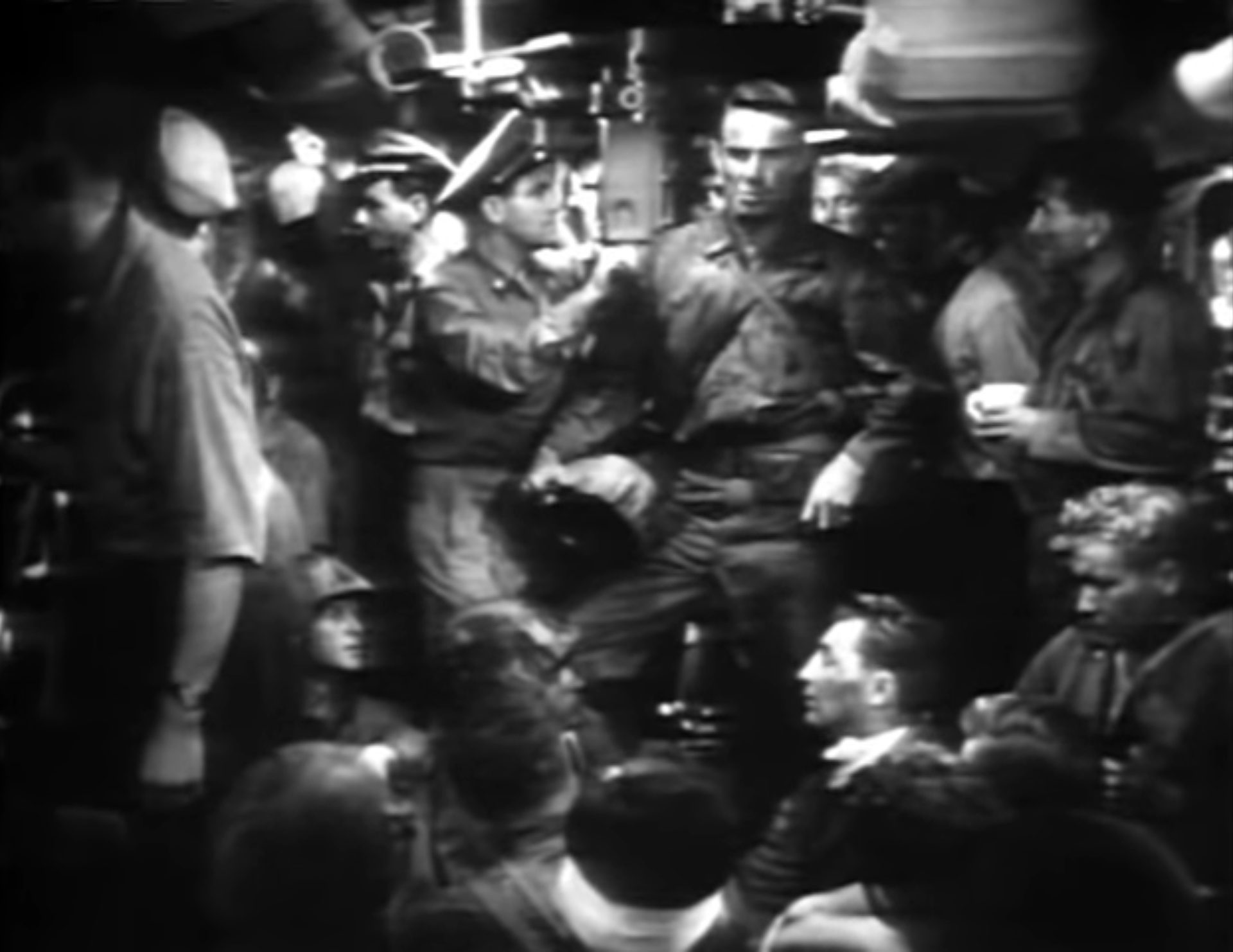 Schwarz-Weiß-Szene: Randolph Scott als Marine-Truppenführer inmitten seiner Soldaten und einiger Besatzungsmitglieder des U-Bootes; neben ihm blickt ein Offizier durch das Periskop.