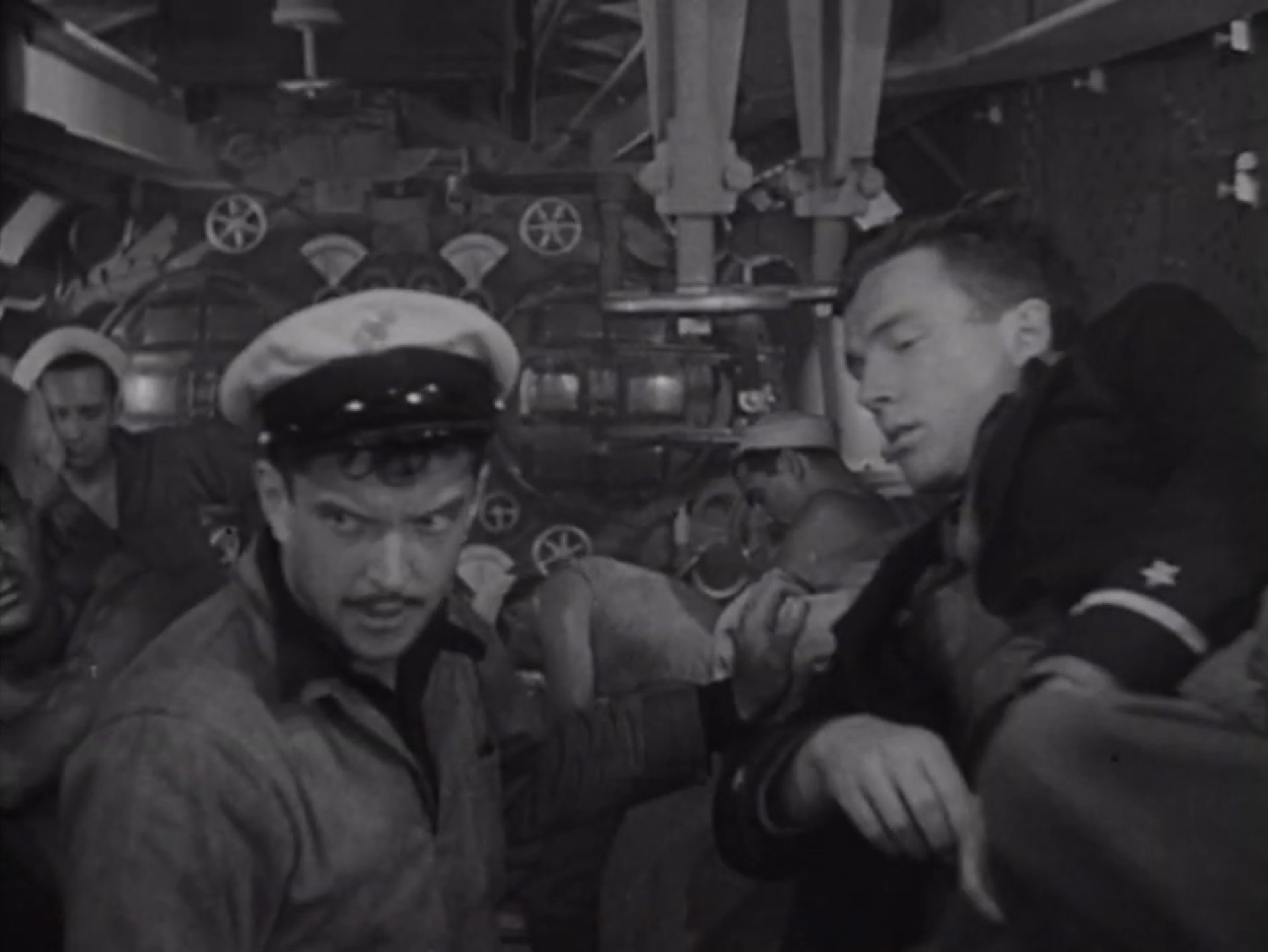 Schwarz-Weiß-Aufnahme: Blick in das U-Boot-Innere, erschöpfte Seeleute im Torpedoraum.