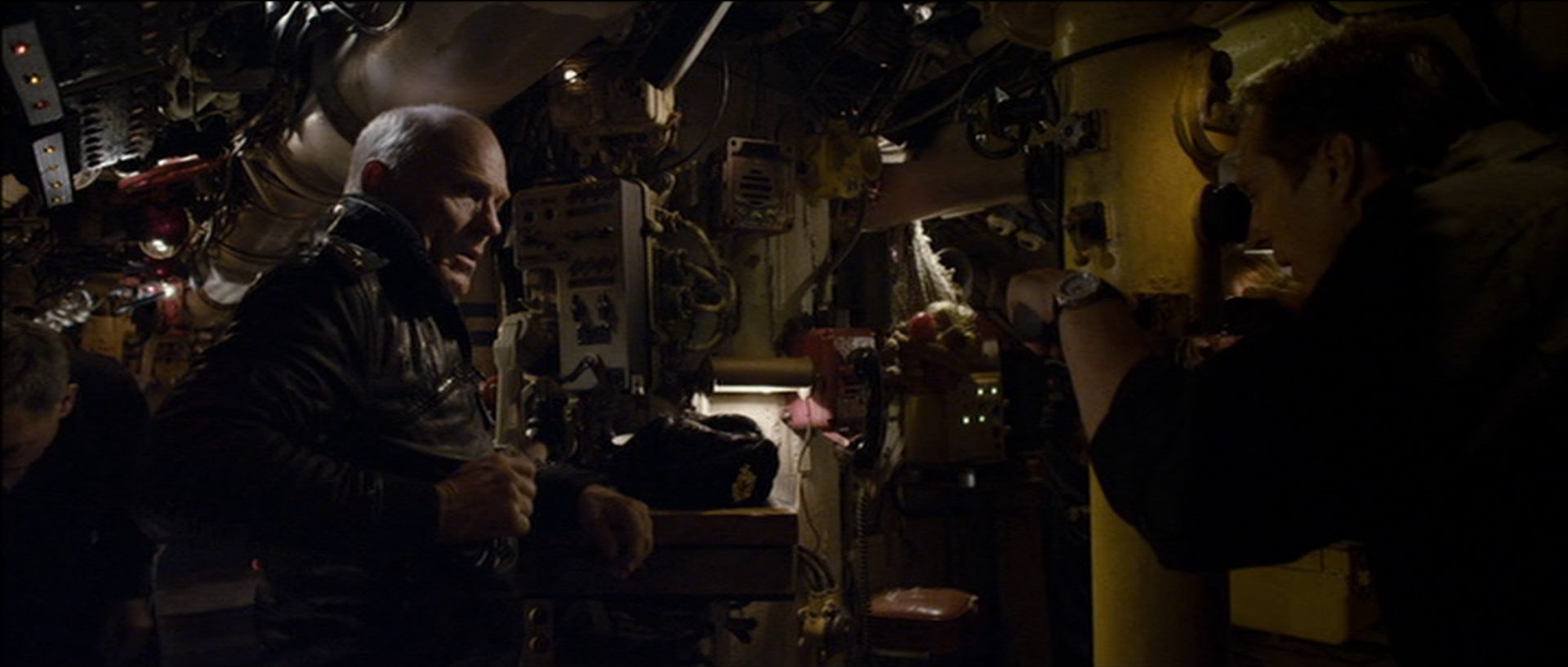 Ed Harris als sowjetischer U-Boot-Kommandant an Bord in beengter Umgebung, ihm gegenüber blickt jemand durch das Periskop.