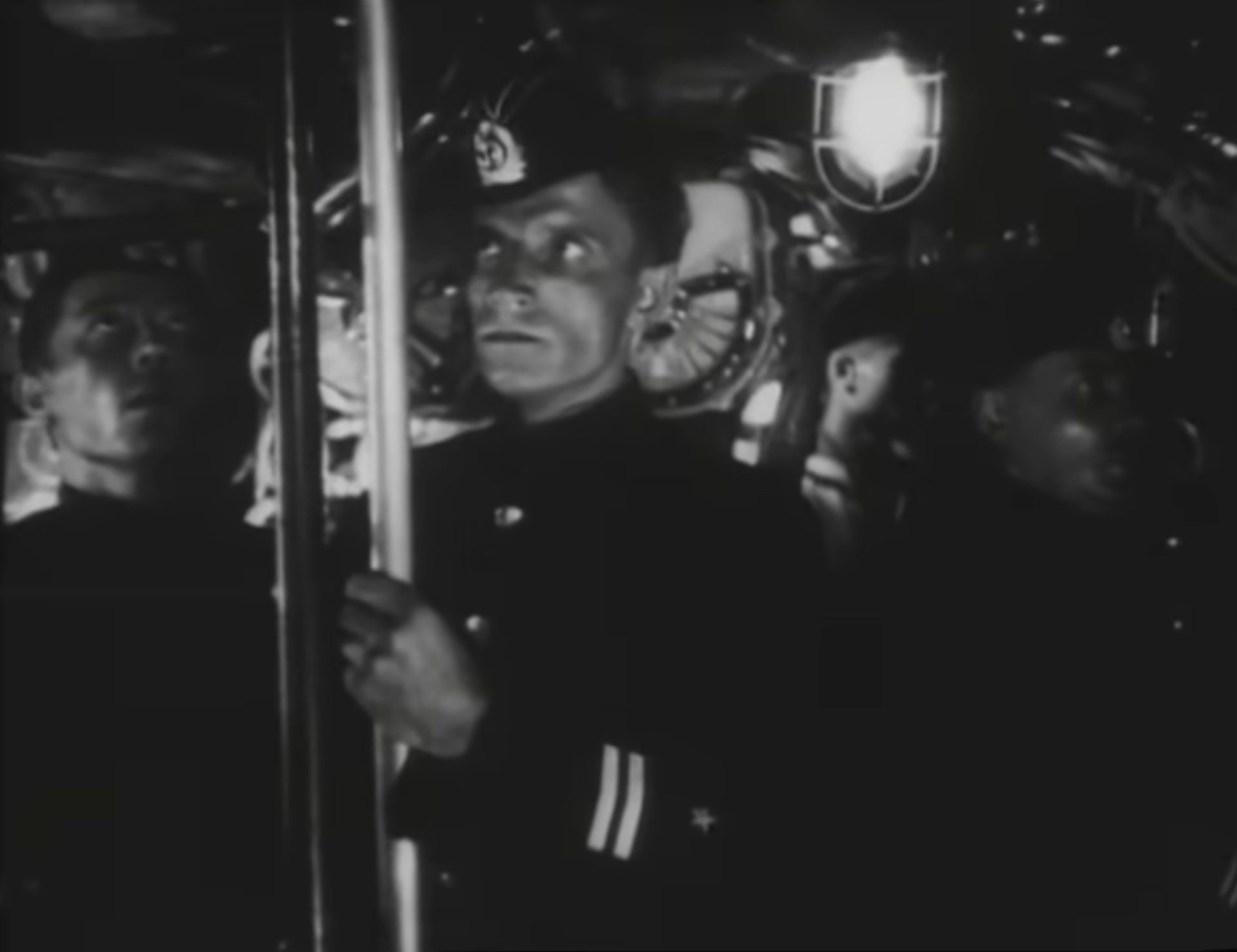Schwarz-Weiß-Szene im Innern eines sowjetischen U-Bootes, die Besatzungsmitglieder blicken besorgt nach oben.