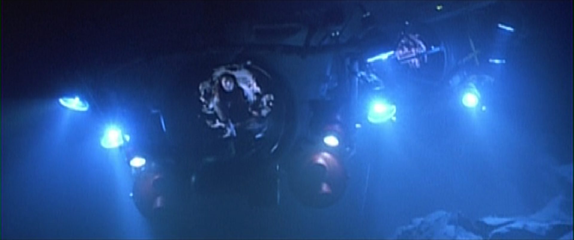 Verfolgungsjagd zweier Mini-U-Boote unter Wasser, die Tiefe wird von einigen Scheinwerfern erleuchtet.