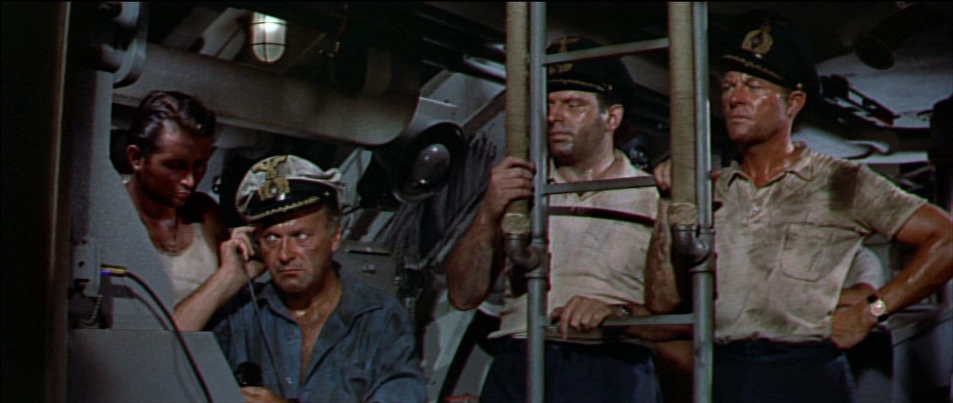 Bridge of a German submarine: Curd Jürgens as captain with a tense look in the presence of three submariners, all sweaty and oily.