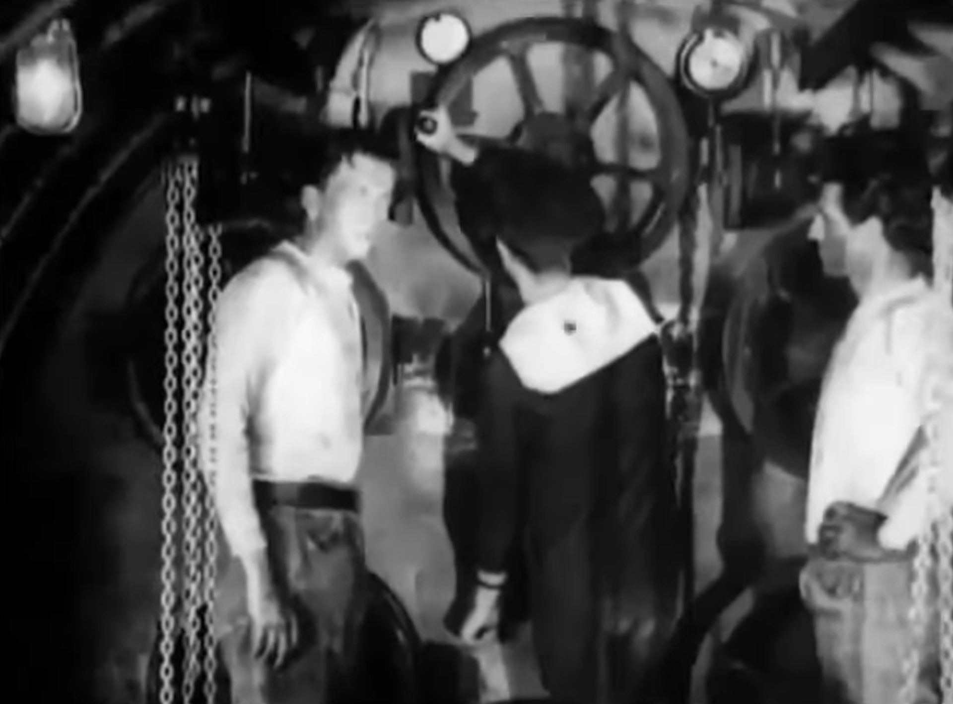 Schwarz-Weiß-Szene mit drei Männern im Torpedoraum.