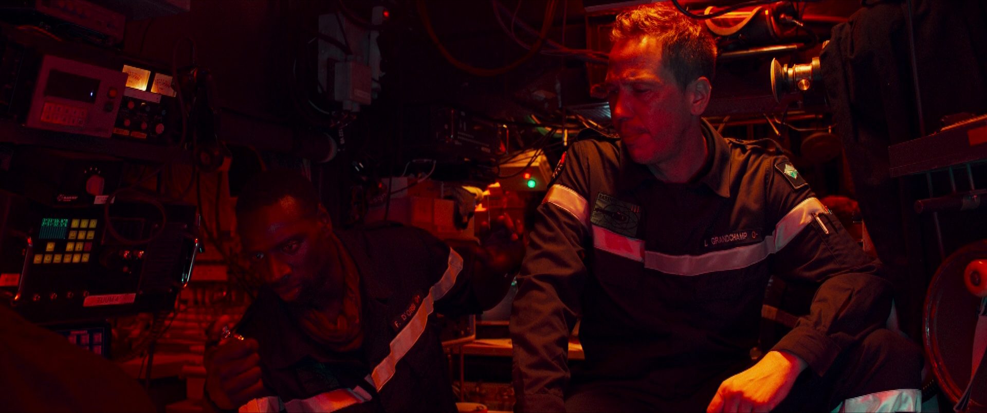 Omar Sy and Reda Kateb as officers on board a French submarine in a precarious situation, surrounded by numerous apparatuses.