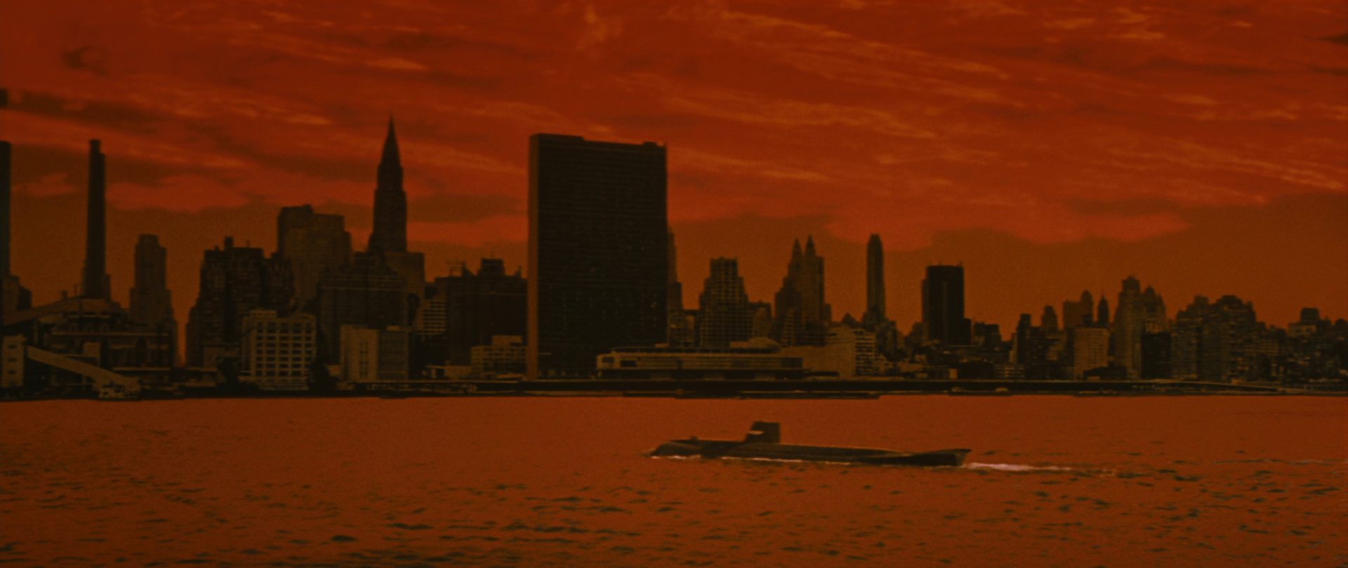 Apokalyptisch rot eingefärbte Szene mit einem aufgetauchten U-Boot mit futuristischer Anmutung vor der Skyline New Yorks mit dem UNO-Hauptquartier im Zentrum.