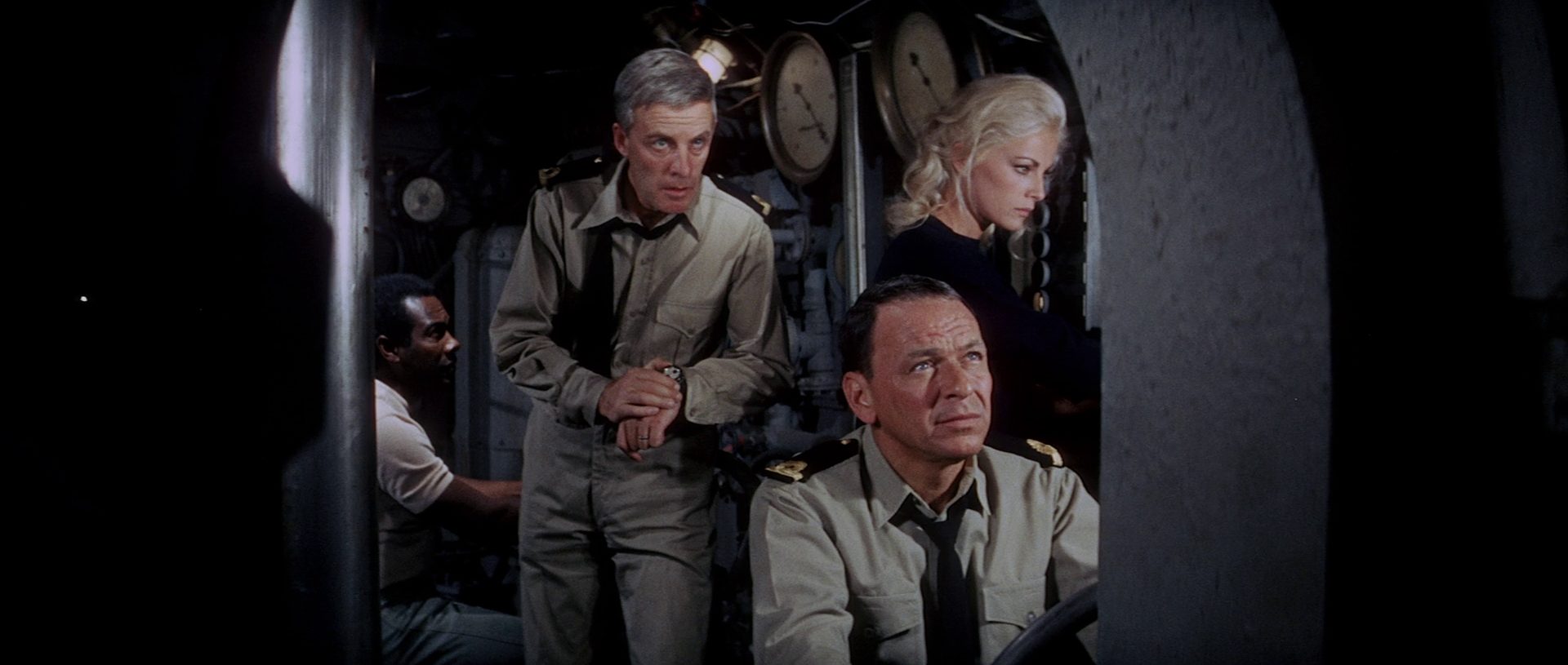 Blick durch ein Schott in die U-Boot-Zentrale mit Alf Kjellin als Kapitän, Frank Sinatra und Virna Lisi als seine Kompliz:innen, alle mit konzentriertem Blick.