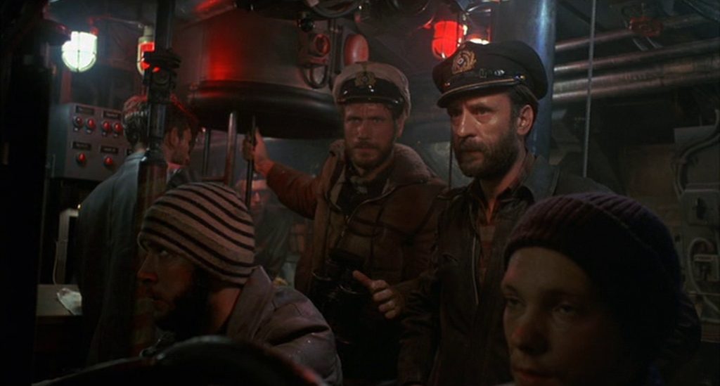 View of the submarine conn with Jürgen Prochnow as commander and Klaus Wennemann as chief engineer with highly concentrated faces in a tense atmosphere, in the foreground two sailors looking at their equipment.