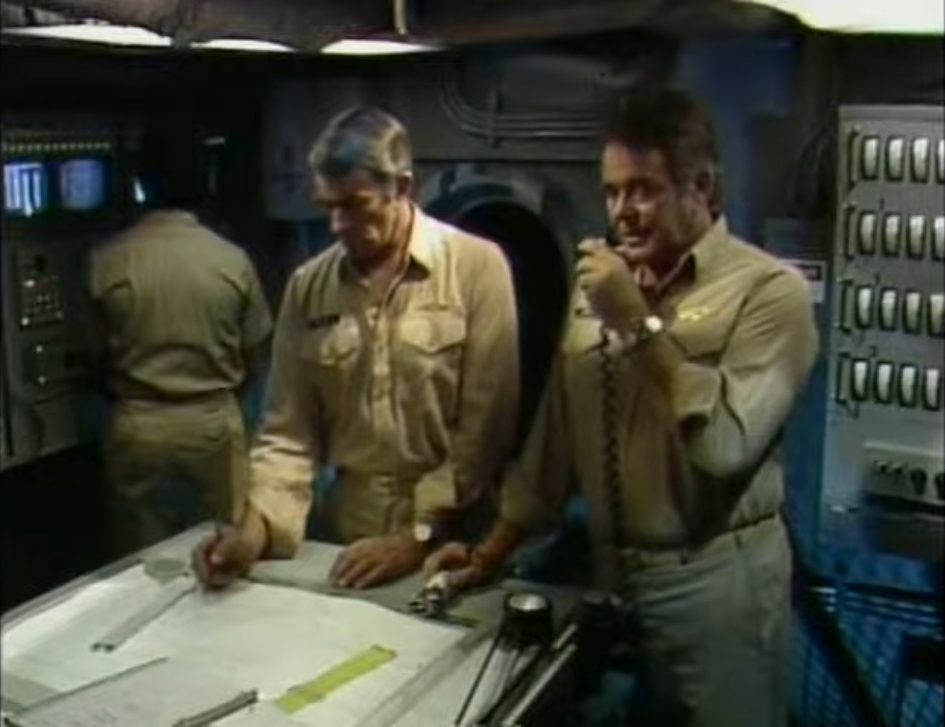 Paul Mantee als Erster Offizier am Kartentisch, neben ihm Stuart Whitman als Kommandant bei einer Durchsage über den Bordfunk.
