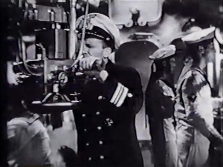 Schwarz-Weiß-Szene mit einem deutschen U-Boot-Offizier in dunkler Uniform mit konzentriertem Blick durch das Sehrohr, im Hintergrund zwei weiß uniformierte Seeleute auf ihren Posten.