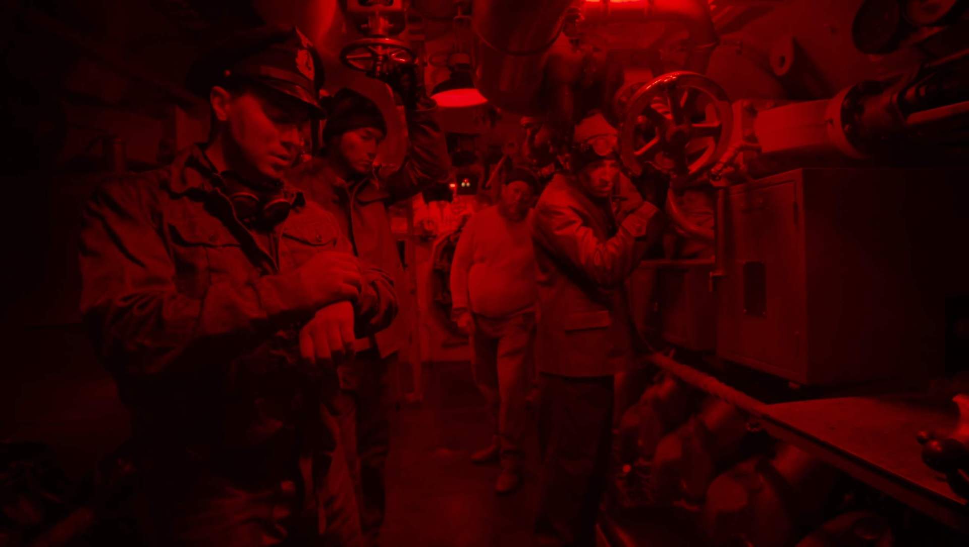 Vier Mitglieder einer deutschen U-Boot-Besatzung im Innern des Bootes bei Rotlicht.