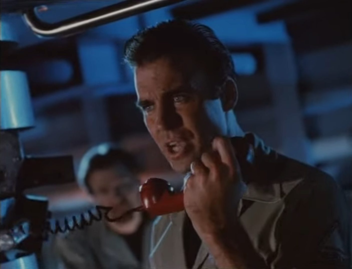 Nahaufnahme von Jeff Fahey als U-Boot-Kommandant Deakins in der spärlich ausgeleuchteten Zentrale; mit konzentriert-bestimmtem Blick spricht er in den Bordfunkhörer.
