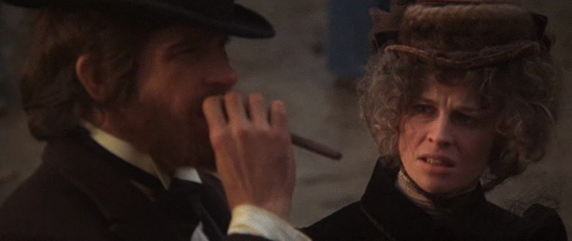Close-up of Warren Beatty as John McCabe with long cigar and Julie Christie as Constance Miller looking at him critically.