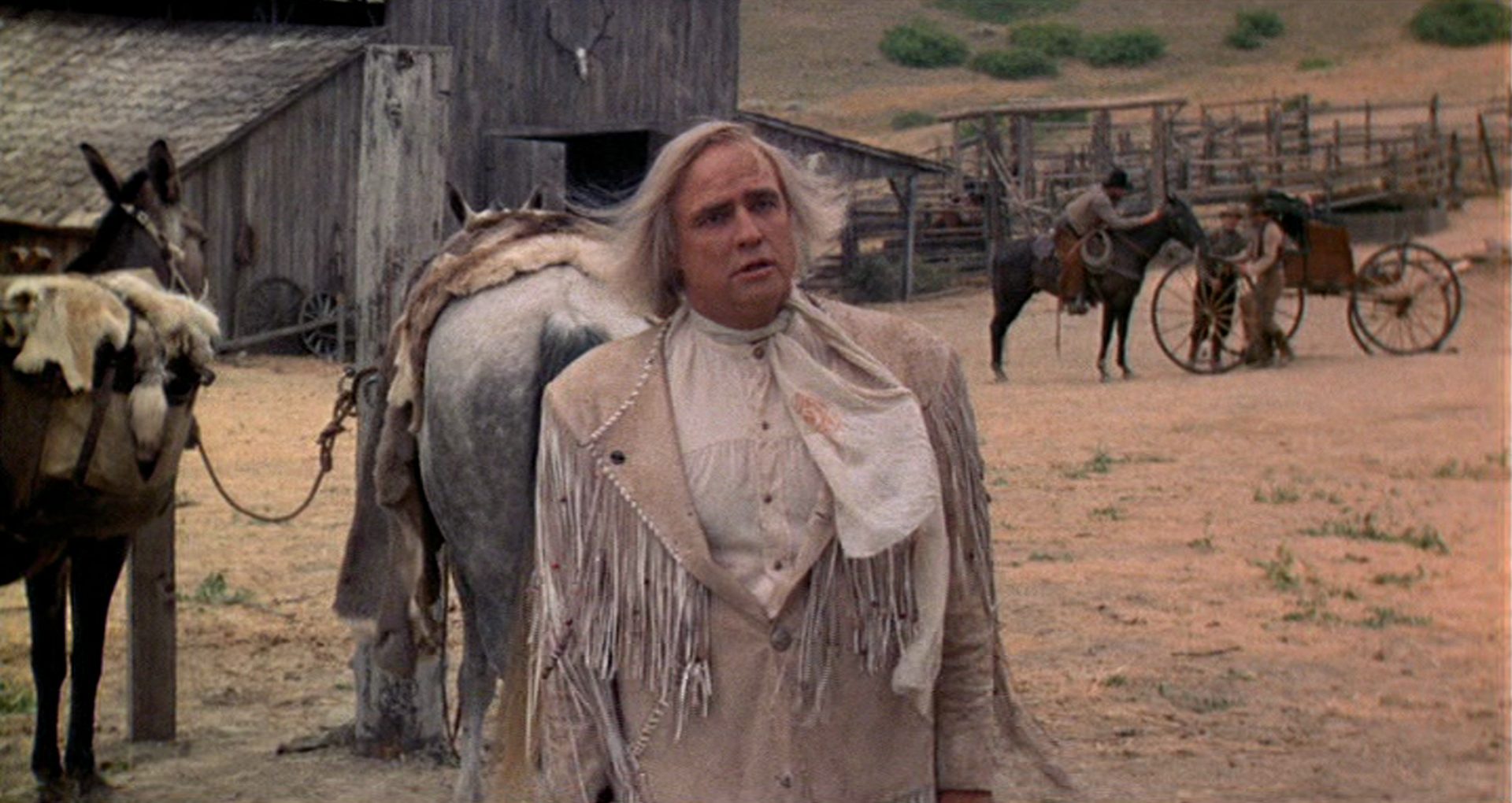 Marlon Brando as an eccentric killer against the backdrop of a ranch building.