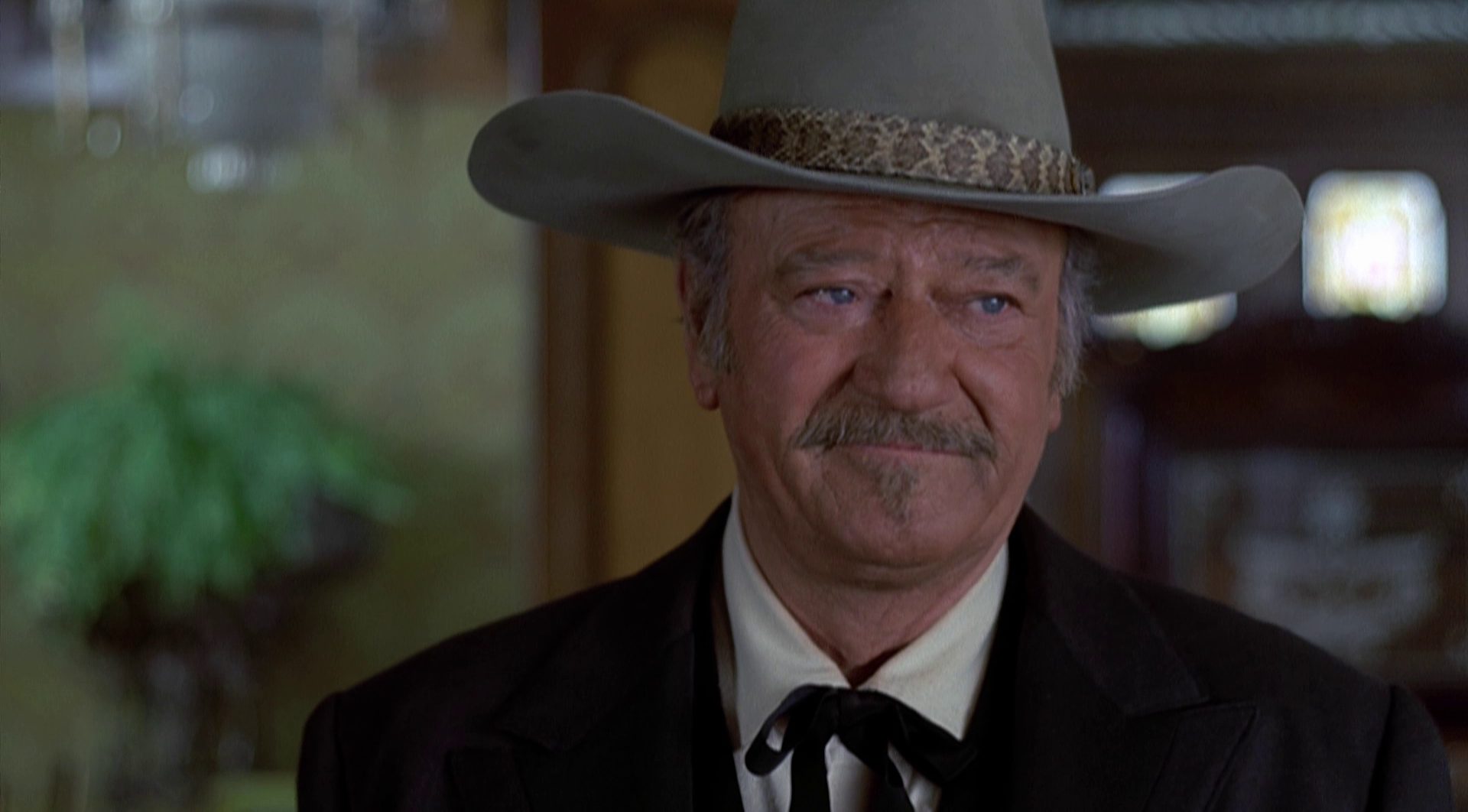Nahaufnahme von John Wayne als J.B. Book mit bedenklichem Gesicht und großem Hut.