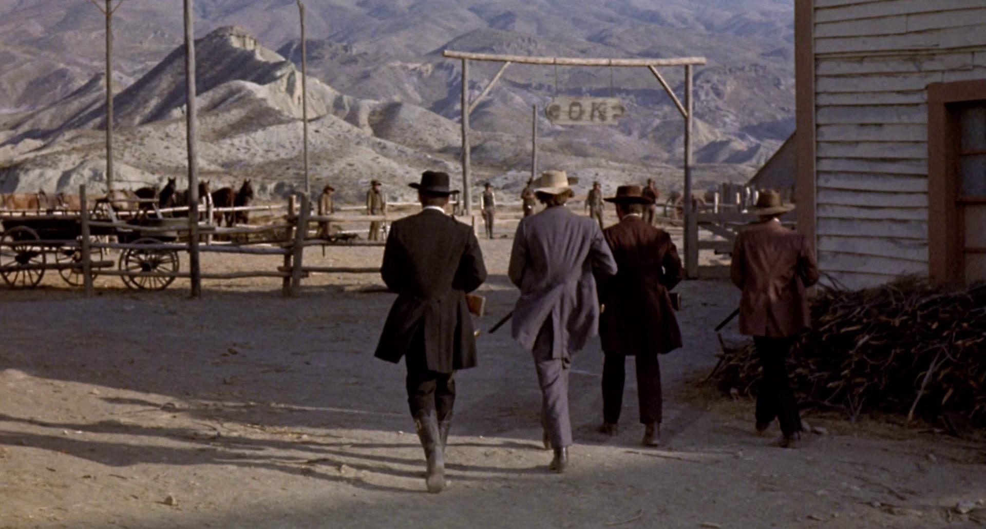Die Earp-Fraktion marschiert auf die Pferdekoppel zu, in der in einer Reihe mehrere Männer warten; über dem Eingang hängt ein kleines Schild mit der Auschrift „O K“.