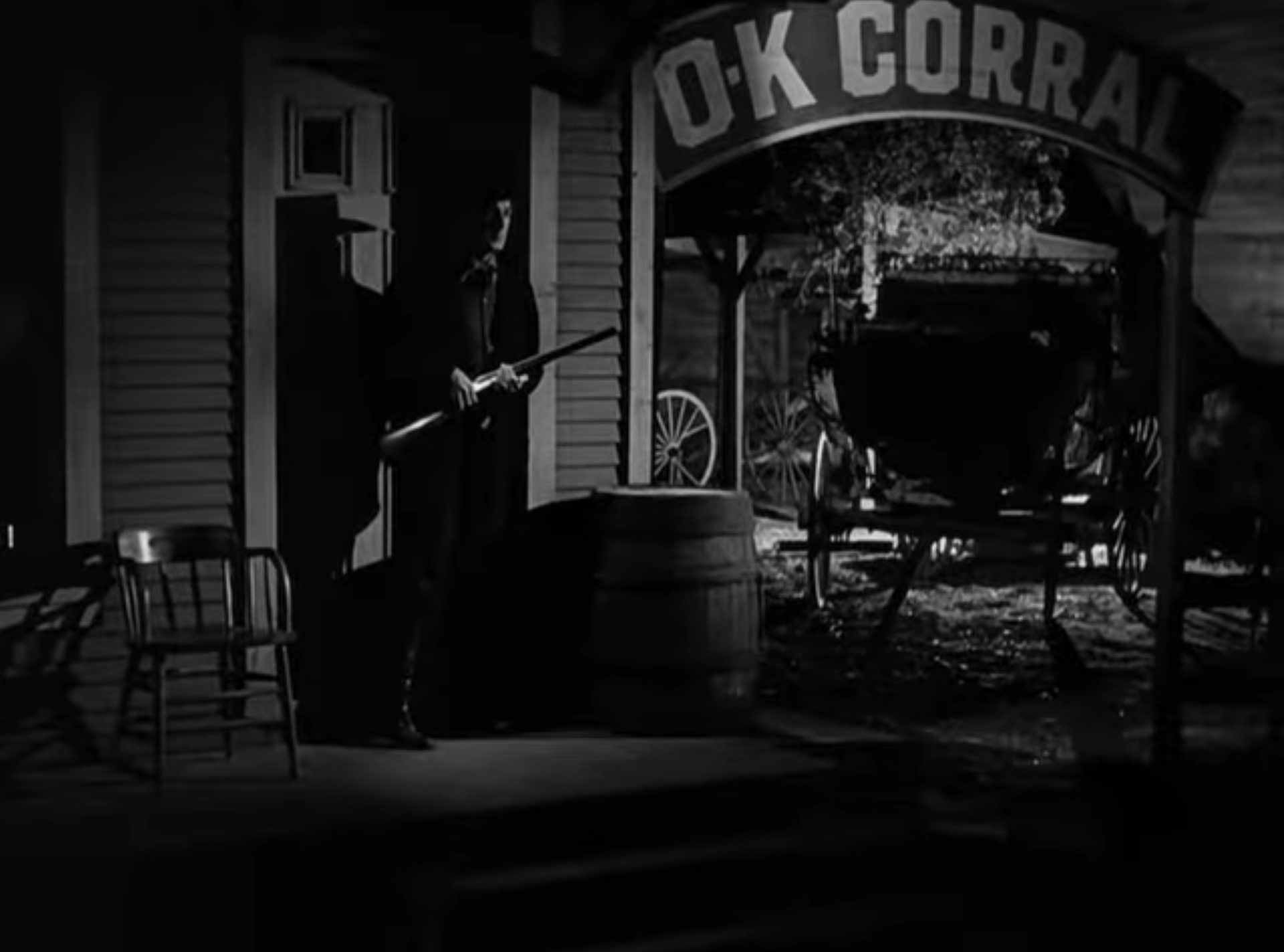 Randolph Scott als Earp mit Gewehr im Anschlag am O.K. Corral in düsterer Atmosphäre.