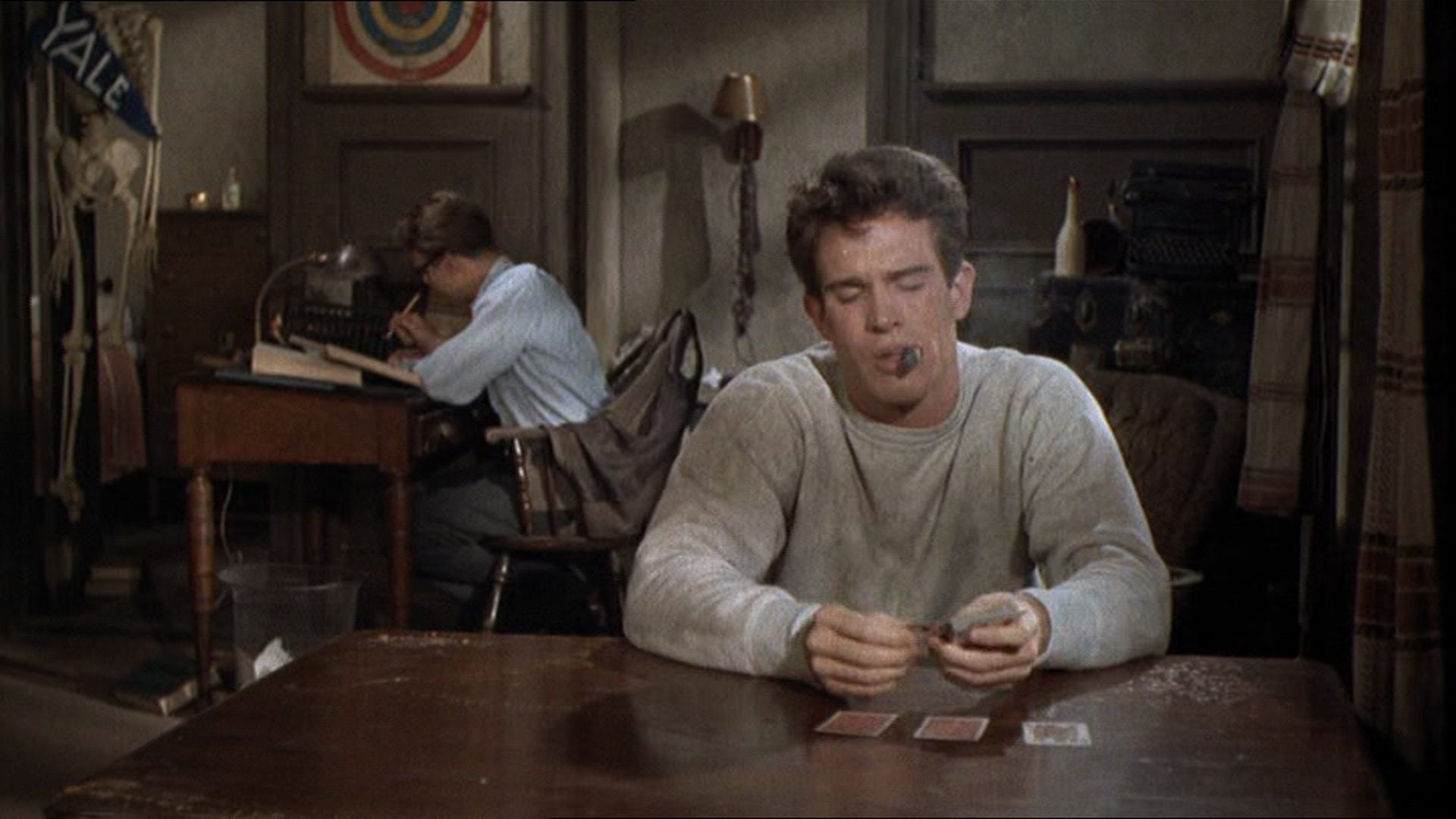 Karges Studentenzimmer, Beatty sitzt mit Zigarre am Tisch, vor ihm drei nebeneinander liegende Karten.