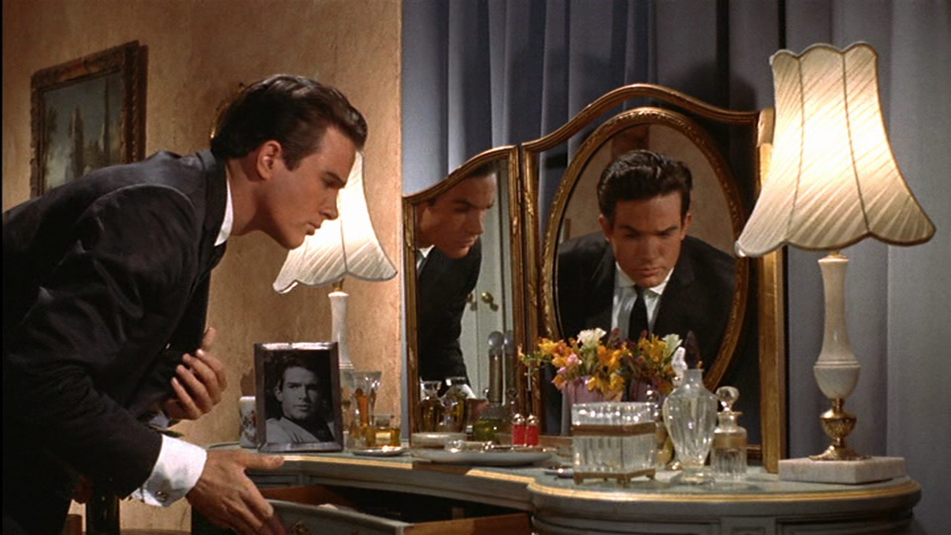 Warren Beatty über eine geöffnete Schublade gebeugt, sein Spiegelbild erscheint im Garderobenspiegel.