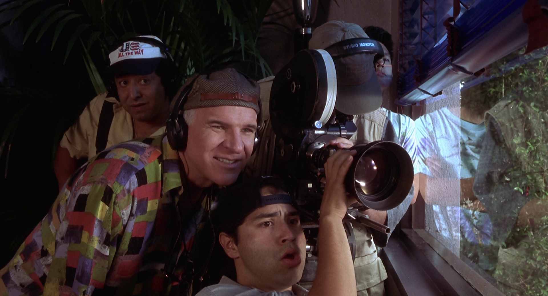 Nahaufnahme von Steve Martin als Regisseur mit Crew an der Kamera während des Drehs einer Szene.