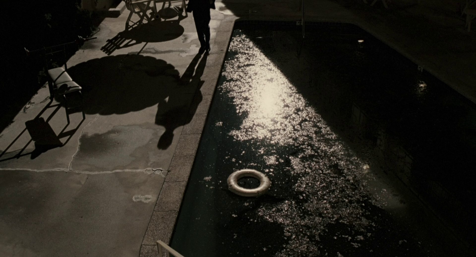 Düstere Szenerie an einem Pool, ein Schatten kündigt eine Person im Hintergrund an.