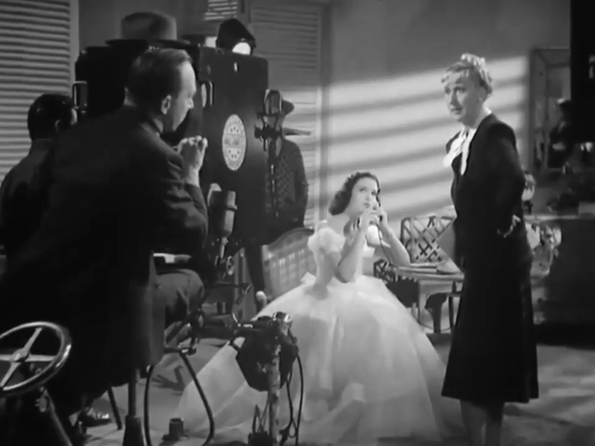 Schwarz-Weiß-Szene mit Linda Darnell als Schauspielanwärterin beim Screentest in Kostüm an einem Telefonapparat, neben ihr Charlotte Greenwood als Schauspielcoach mit entschiedenem Blick zum Kameramann, der hinter seinem Apparat hervorlugt.
