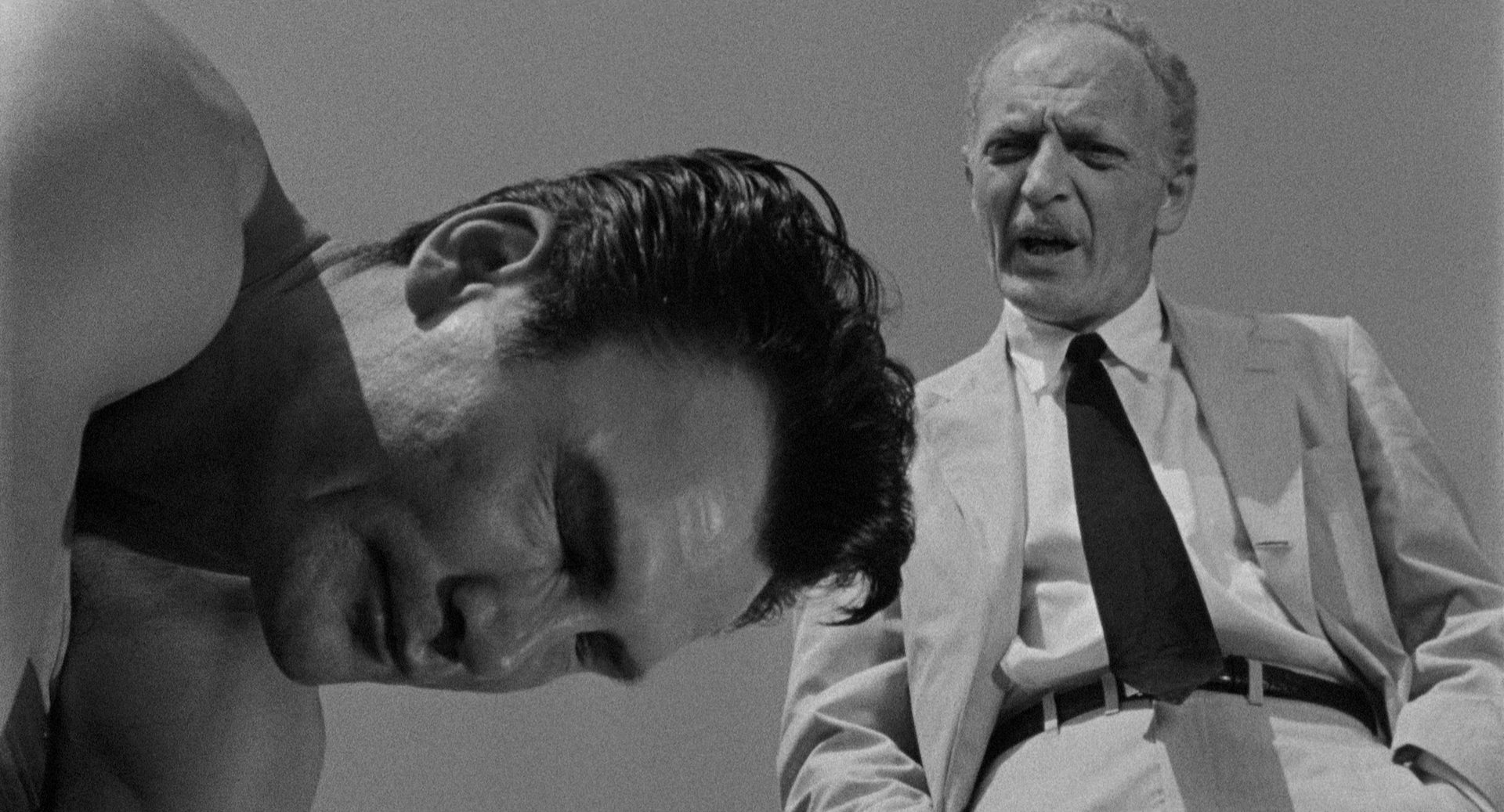 Nahaufnahme des angestrengten Gesichts von Jack Palance als Hollywoodstar Charlie Castle im Gespärch mit seinem Agenten, gespielt von Everett Sloane.