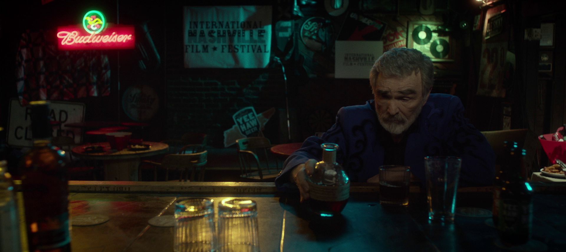 Der alte Burt Reynolds als Vic Edwards an der Theke einer spärlich ausgeleuchteten Bar in Nashville beim Griff zum Whiskey.