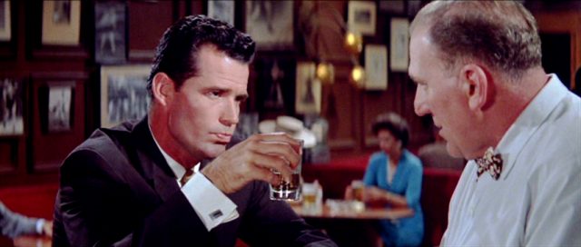 Fred (James Garner) im Gespräch mit dem Barkeeper, während er in einer Hand ein Longdrink-Glas hält