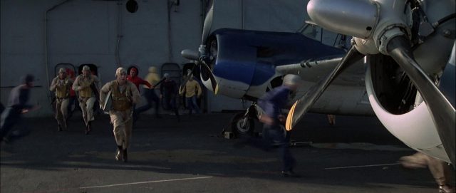 US-amerikanische Piloten eilen auf einem Flugzeugträger zu ihren bereitstehenden Maschinen.