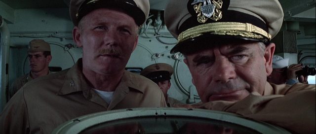 Nahaufnahme von Glenn Ford als US-Navy-Befehlshaber auf Brücke mit Offizier.