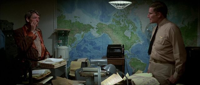 Hal Holbrook und Charlton Heston als US-amerikanische Offiziere in einem chaotischen Büro mit großer Karte.