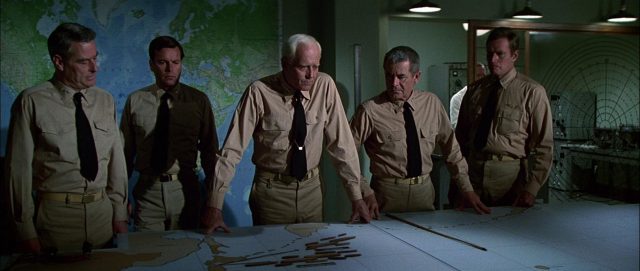 Robert Webber, Robert Wagner, Henry Fonda, Glenn Ford und Charlton Heston als Navy-Offiziere mit betretenen Mienen am großen Kartentisch.