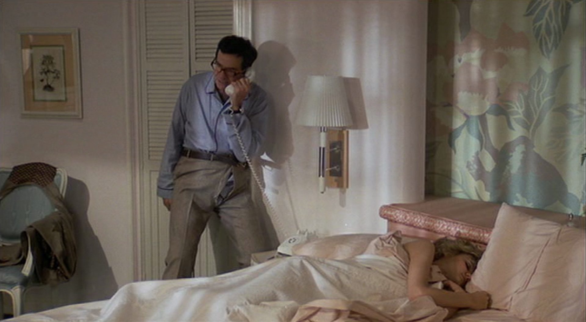 Walter Matthau telefoniert in angestrenger Haltung und offener Hose in seinem Hotelzimmer, während auf dem Bett eine Frau schläft.