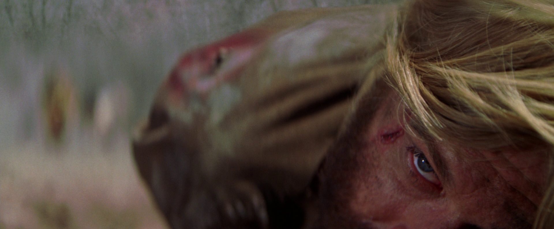 Extreme Nahaufnahme von Robert Redfords Gesicht; Johnson liegt am Boden und hat nebenm dem rechten Auge eine blutige Schramme.