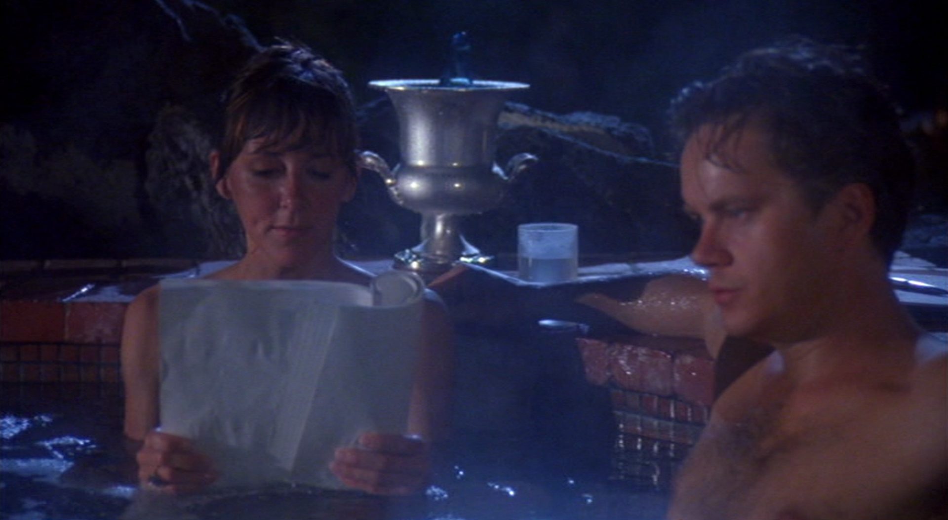 Nahaufnahme von Bonnie Sherow (Cynthia Stevenson) und Griffin Mill (Tim Robbins) abends im Pool; sie liest ein Skript, er schaut nachdenklich.