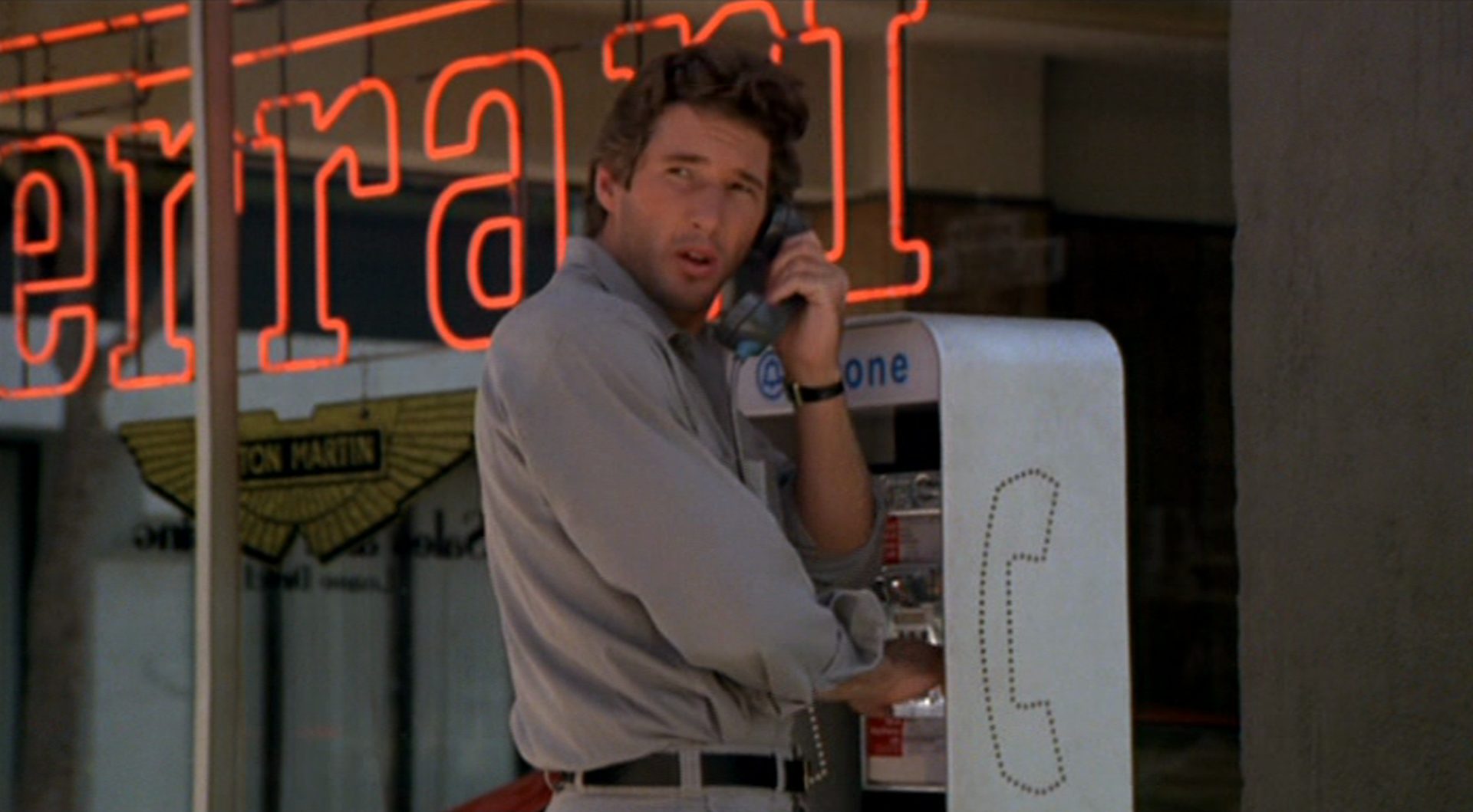 Richard Gere als Julian Kaye, der ein Münztelefon benutzt; im Hintergrund sieht man die Ferrari-Wortmarke.