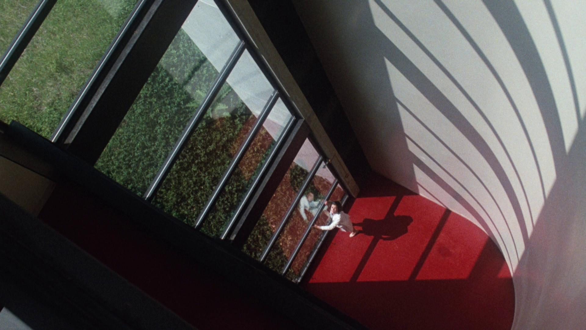 Klaustrophobische Szene: Blick von oben in der Ecke eines großen Gebäudes; am mehrere Etagen unterhalb liegenden Boden blickt Wheeler herauf.
