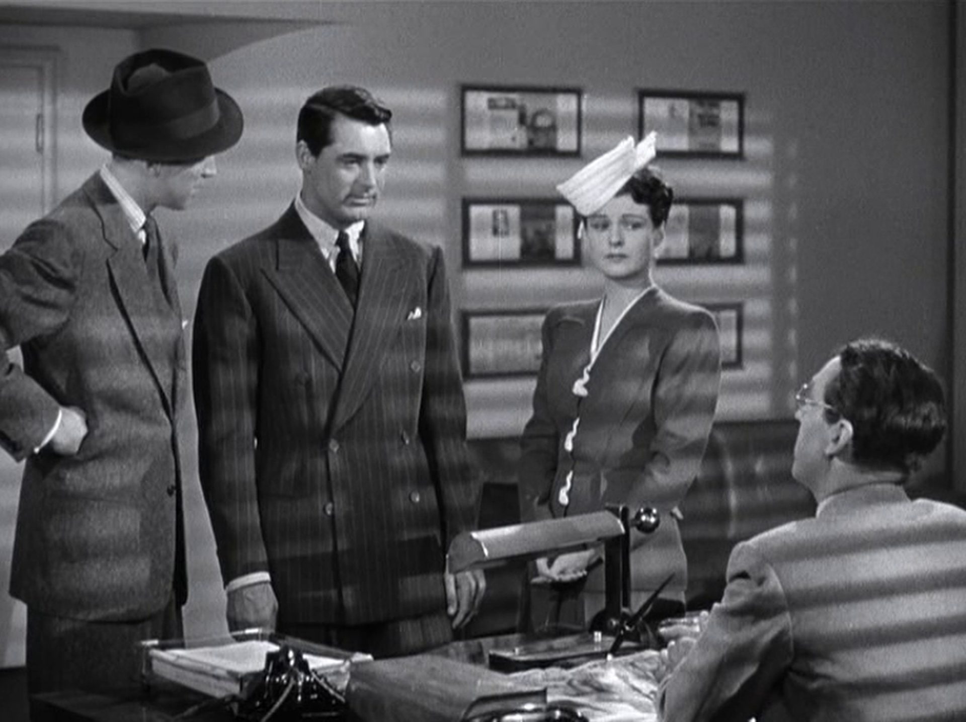 James Stewart, Cary Grant und Ruth Hussey als Connor, Haven und Imbrie vor dem Schreibtisch des Magazinchefs in dessen Büro.