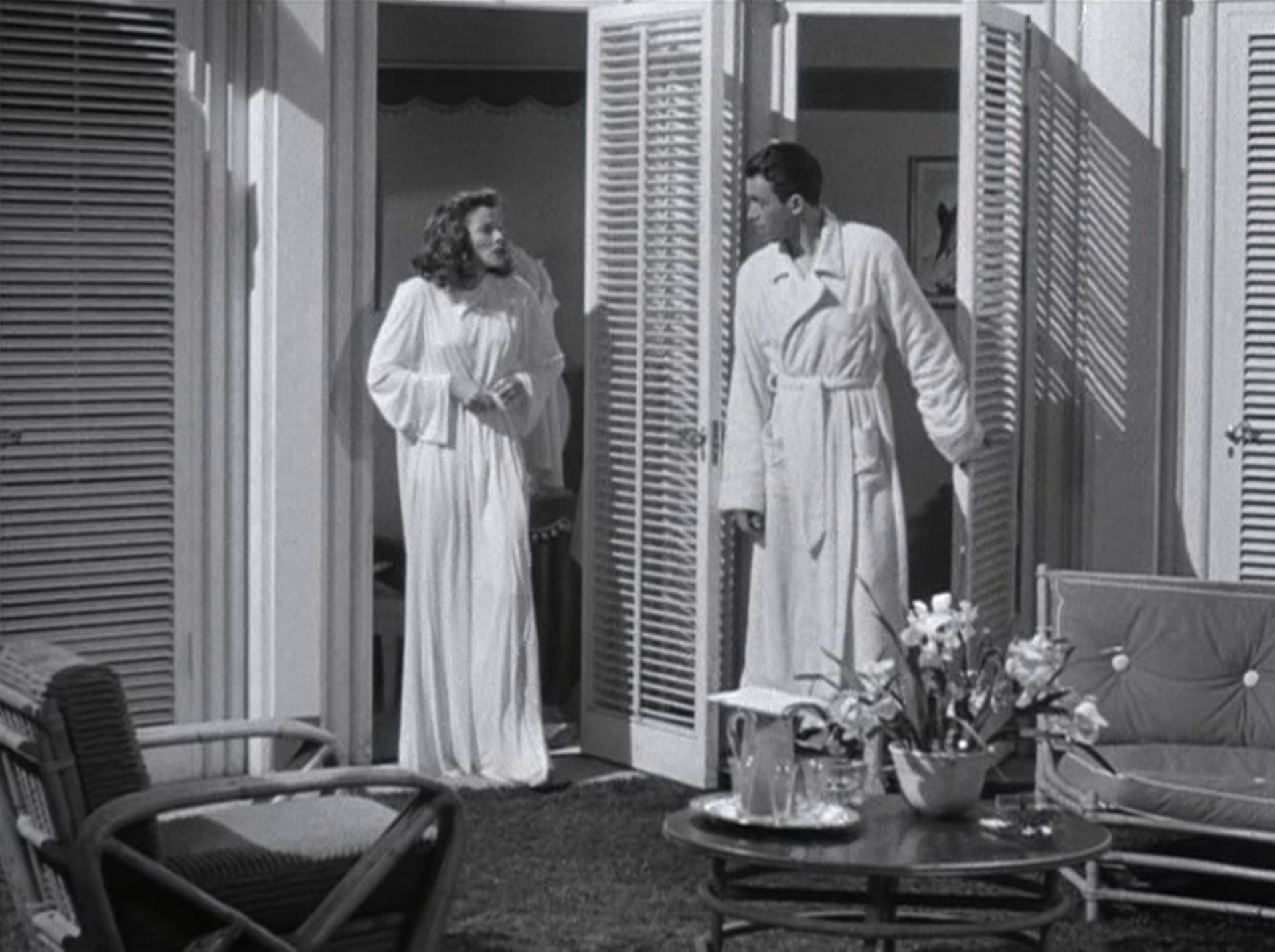 Katharine Hepburn und James Stewart in Bademänteln im sehr hellen Umkleidebau des Swimmingpools.