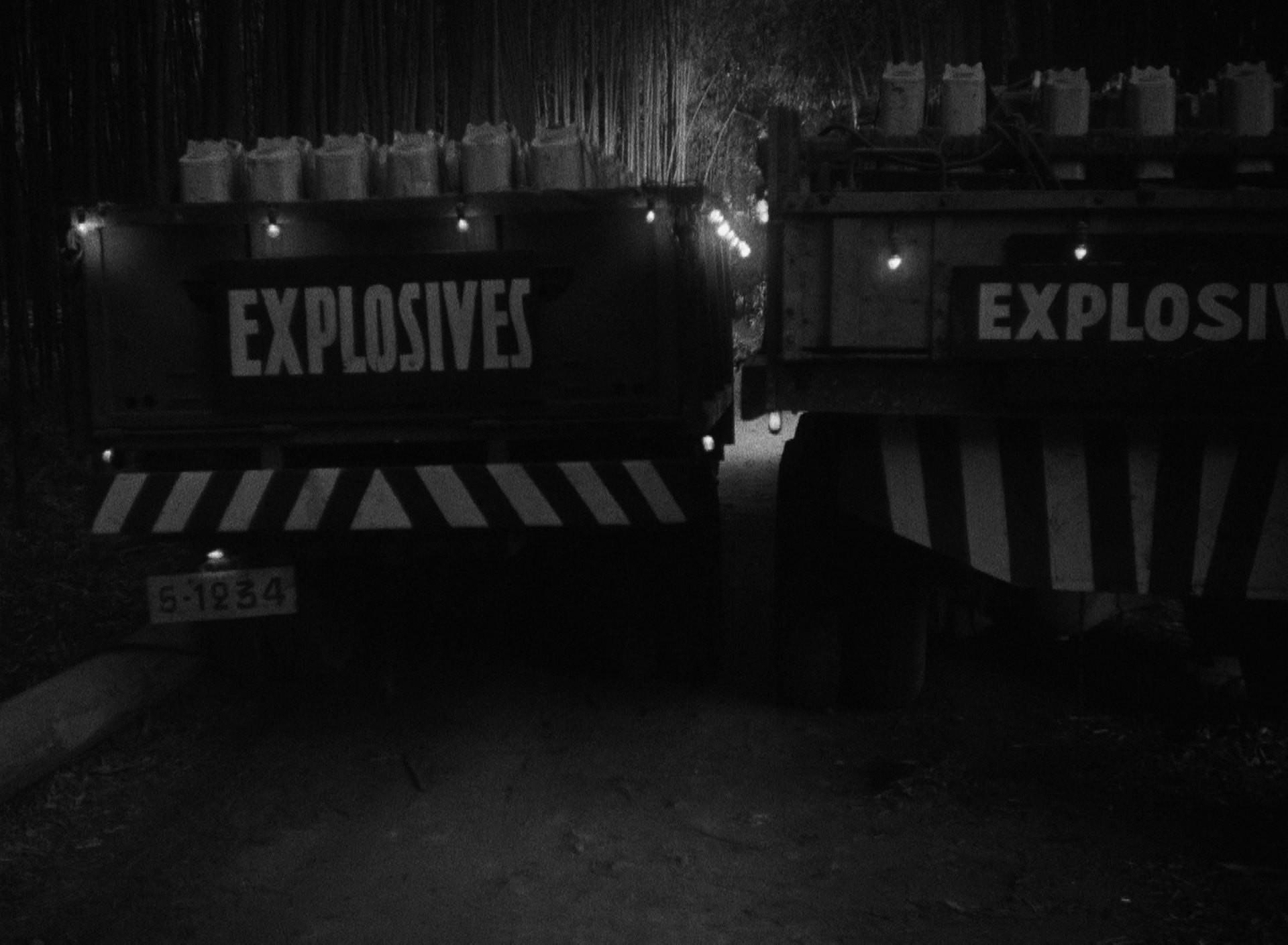 Nachtaufnahme: Rückseite der beiden parallel zueinander platzierten Lkws mit der Aufschrift „Explosives“.