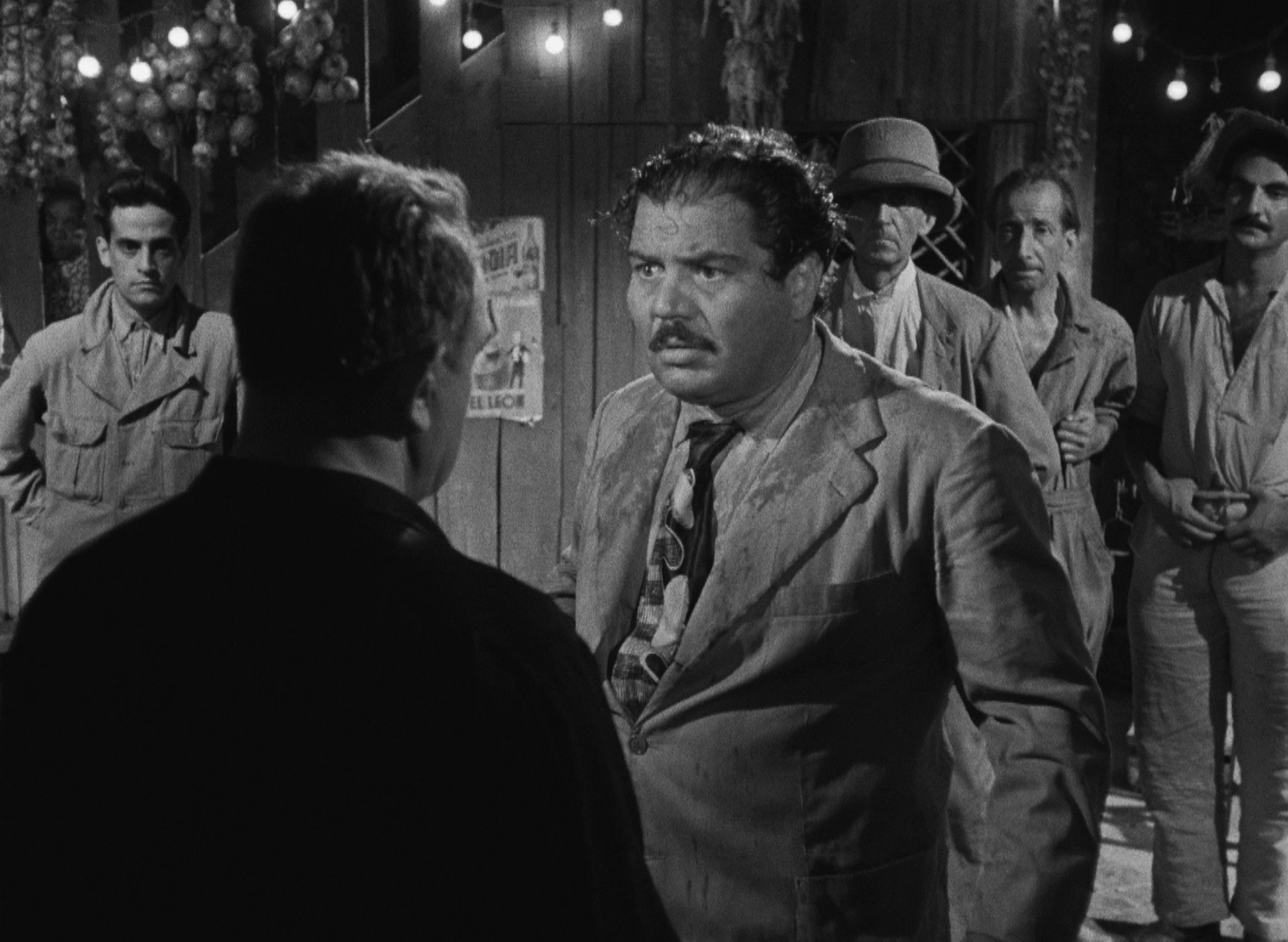 Folco Lulli als Luigi in feiner Kleidung, Kopf und Kragen nass, in einer aggressiven Konfrontation in der Hotelbar.
