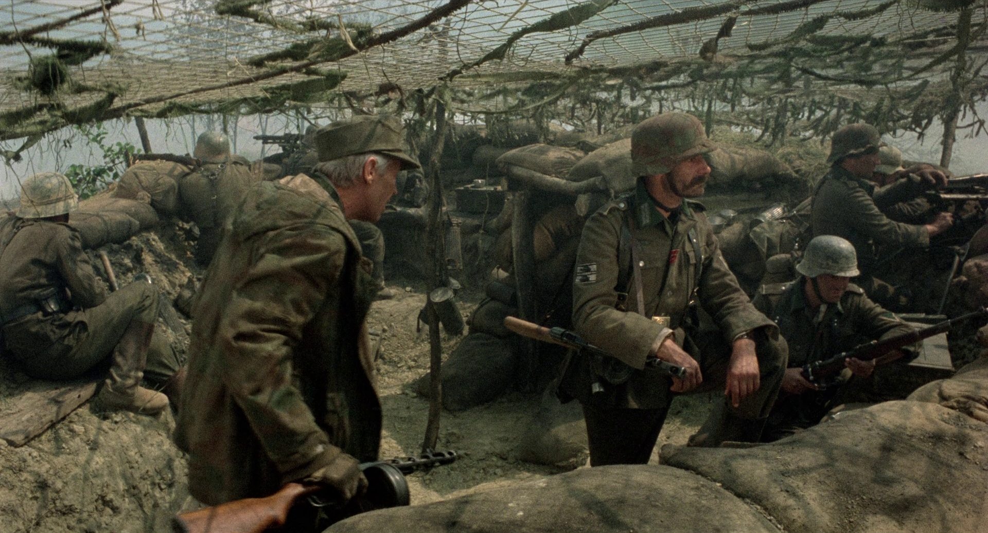 Fred Stillkrtauth als Schnurrbart in einer deutschen Stellung unter einem Tarnnetz.